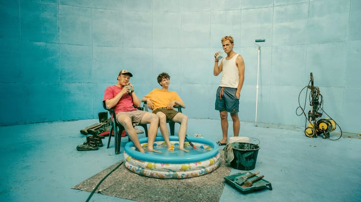 BlaBla (Sebastian Jakob Doppelbauer, l.), Carlo (Jeremias Meyer, M.) und Aydin (David Ali Rashed, r.) haben eine Güllegrube blau gestrichen und wollen daraus ihren eigenen Pool mit Beach basteln.