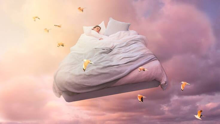 A sleeping girl floats on a bed in the sky 