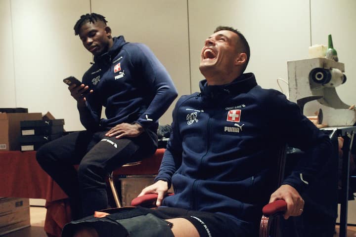 The Pressure Game â Im Herzen der Schweizer NatiFolge 4Granit Xhaka im Gespräch mit dem Nati-Schuhmacher «Schüppi»: Breel Embolo (hinten l.), Granit Xhaka (r.)2023Copyright: SRF/stories AG